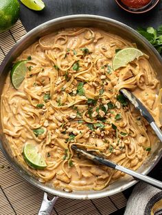 a skillet filled with noodles and topped with limes