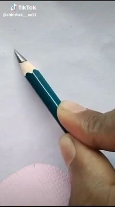 a person holding a pencil in their left hand and pointing it at the tip of the pen