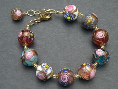 "The Fiorato (flower) beads, that some people call \"wedding cake beads\", on this bracelet, are Vintage Murano Glass Beads. This type of handmade, lamp worked Murano glass, Venetian Beads, are some of the first beads I ever bought in Venice, Italy. The assortment of 14-15 mm, round beads were made one-by-one under the flame. The glass maker starts with a Murano glass cane (or rod) to make the base color, and then adds an Aventurina (copper filings), band around the center of the bead. Next the Multicolor Round Beads Bracelets For Weddings, Elegant Round Beads Bracelets For Celebrations, Elegant Multicolor Flower Beaded Bracelets, Adjustable Polished Beads Bracelets For Wedding, Czech Glass Round Jewelry For Wedding, Elegant Czech Glass Bracelets With Large Beads, Elegant Multicolor Beaded Bracelets For Wedding, Elegant Round Czech Glass Beads, Elegant Single Strand Czech Glass Beads