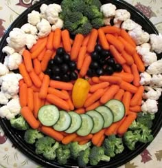 a platter with carrots, cauliflower and cucumbers in the shape of a bird