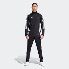 a man standing in front of a white background wearing black and white adidas tracksuits