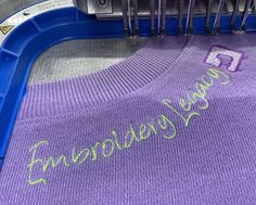 a purple sweater with the word embrown on it is hanging from a clipboard