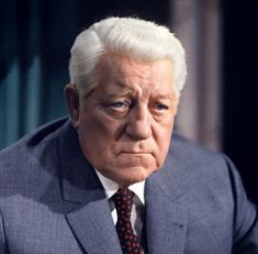 an older man in a suit and tie looking at the camera with serious expression on his face