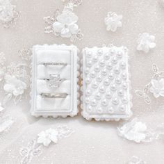 two wedding rings in a box on a white background with pearls and flowers around them