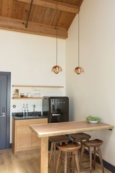 a kitchen with a table and stools next to a refrigerator in the middle of it