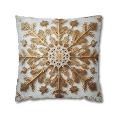 a gold and white pillow with an intricate design on the front, featuring leaves and flowers