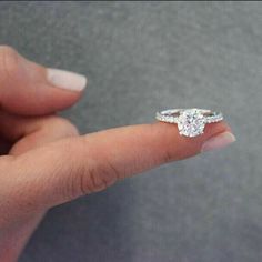 a woman's hand holding an engagement ring with a diamond on the middle finger