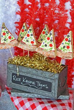 three small pizzas on sticks in a tinsel box with red and white checkered tablecloth