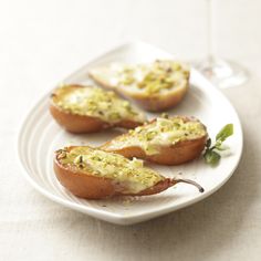 three baked potatoes on a white plate next to a glass of wine