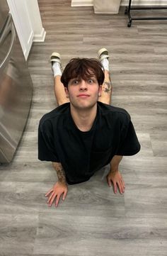 a man laying on the floor in front of a refrigerator