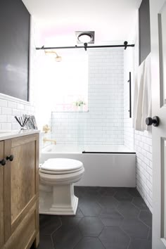 a white toilet sitting next to a bath tub in a bathroom under a light fixture