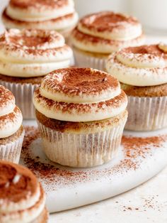 several cupcakes with white frosting and cinnamon sprinkles on a plate