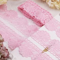 pink crochet lace on white paper next to flowers