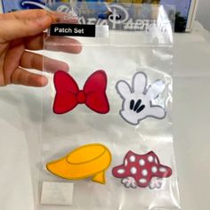 someone is holding up some stickers on a bag that has mickey mouse and other disney characters in it