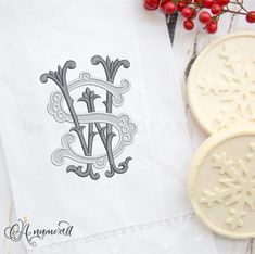 the monogrammed dish towel has snowflakes on it and is next to a cookie