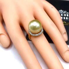 A lustrous pearl, cocktail ring is a need for every lady in the world. What could get you more attention than having this huge, exotic, and sparkling pearl ring on your finger while holding a glass of wine? We are presenting you with a Huge GOLDEN SOUTH SEA PEARL, absolutely natural color and TOP AA+ luster, 14 mm in size, surrounded by 22 pieces of hand-set F/VS superb quality diamonds, weighting at 0.64 carat. Set in handcrafted, one of a kind 18K solid white gold ring, weighting at 8.0 grams. Elegant Silver Pearl Ring For Party, Elegant Pearl Ring For Party, Elegant Gold Pearl Ring For Party, Gold Pearl Rings For Party, Party Gold Rings With Pearl, Party Gold Pearl Rings, Golden South Sea Pearls, Sea Pearls, South Seas