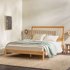 a bed sitting on top of a wooden floor next to a white wall in a bedroom