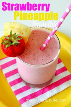 a strawberry pineapple smoothie in a glass on a yellow plate with pink and white stripes