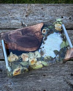 a wooden table topped with a glass plate covered in flowers next to a piece of wood