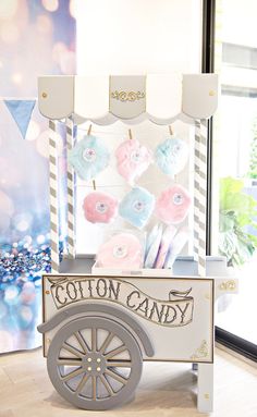 an ice cream cart with cotton candy on it in front of a window that says cotton candy