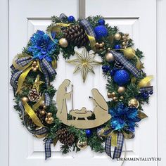 a christmas wreath with a nativity scene hanging from it's center and decorations on the front door