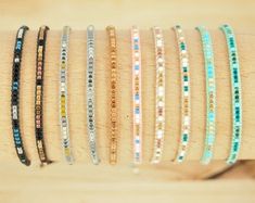 a bunch of bracelets that are on top of a wooden table and one is in different colors