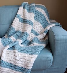 a blue couch with a crocheted blanket on it