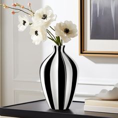 a black and white vase with flowers in it on a table next to a book