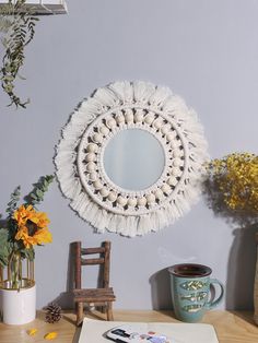 a table topped with a mirror and vase filled with flowers next to a wooden chair