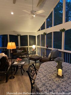 a living room filled with furniture next to large windows covered in blinds and lamps on either side of the couches