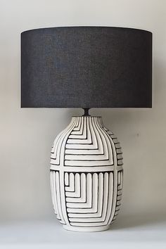 a black and white lamp sitting on top of a table next to a gray lampshade