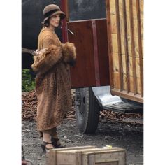 a woman standing next to a trailer with a fur stoler on it's shoulder