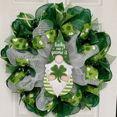 a st patrick's day wreath with green and white decorations on the front door