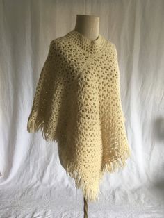 a crocheted shawl on a mannequin stand with a white background