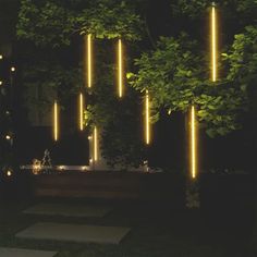 some lights that are on the side of a building in the night time, with trees and grass