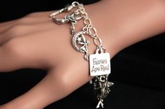 "A collection of silver plated fairy themed charms have been dispersed around a shimmering silver plated bracelet chain in this handmade charm bracelet. This Fairies are Real charm bracelet is then completed with a lobster clasp and a 1/2 inch of chain at the end for adjustable sizing. Charms in this bracelet include eight assorted fairy charms, and a \"Fairies are Real\" charm. ● Sizing ● To determine your bracelet size, do a snug measurement of your wrist's circumference, then add 1/2 an inch. Whimsical Silver Charms For Gifts, Whimsical Silver Dangling Charms, Whimsical Nickel-free Charm Bracelet Gift, Whimsical Nickel Free Charm Bracelet Gift, Adjustable Silver Fantasy Bracelet, Silver Fantasy Bracelet, Whimsical Silver Bracelet Jewelry, Whimsical Silver Charm Bracelet, Handmade Themed Silver Charm Bracelet