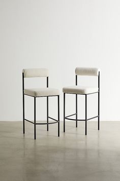 two chairs sitting next to each other on a cement floor in front of a white wall