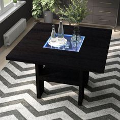 a coffee table with two vases on it in front of a window and a chevron rug