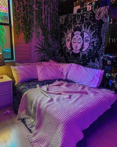 a bed with purple sheets and pillows in a room filled with posters on the wall