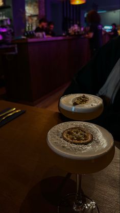 two pizzas sitting on top of each other on stools in front of a bar