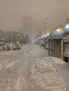 the snow is piled up on the sidewalk in front of some buildings and street lights