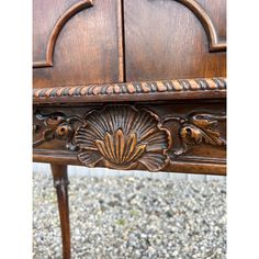 an old wooden bench with carvings on the top and bottom part, sitting in gravel