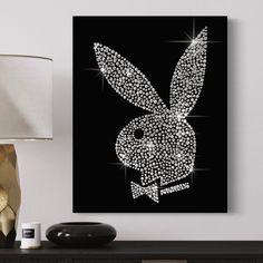 a black and white bunny rabbit art piece on a wall next to a table lamp