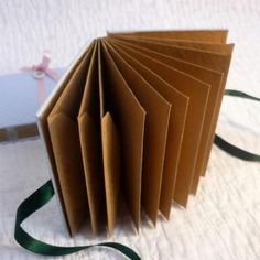 an open book is sitting on a bed with a green satin ribbon around it and the pages have been folded