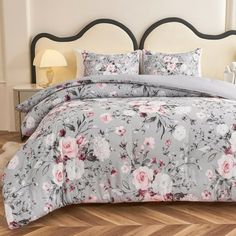 a bed with floral comforter and pillows on top of it, in a bedroom