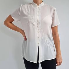 Gorgeous, cheongsam style blouse in white with a beautiful floral embroidery across the front and collar. It has a straight shape, mandarin collar, short sleeves, six buttons and side slits. The blouse is made from a lightweight fabric. A perfect, smart blouse for any occasions. Made by St Michael. 100% polyester. No size label, would fit Medium size. Measurements when laid flat are: Pit to pit: 54cm Waist: 51cm Length: 68cm. Excellent condition, as new. B. Short Sleeve Blouse For Summer Wedding, Classic Short Sleeve Tops For Wedding, Summer Wedding Short Sleeve Blouse, Fitted Stand Collar Blouse For Summer, White Stand Collar Tops For Daywear, Fitted Summer Blouse With Stand Collar, White Short Sleeve Formal Blouse, Formal White Short Sleeve Blouse, Classic Embroidered Short Sleeve Top