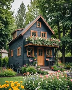 a blue house with lots of flowers in the front yard