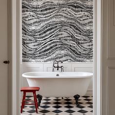 a white bath tub sitting next to a black and white wall