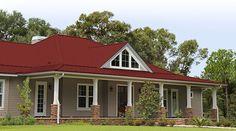 a house with a blue metal roof and white trim on the front porch is surrounded by greenery