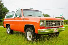 an orange truck parked on top of a lush green field